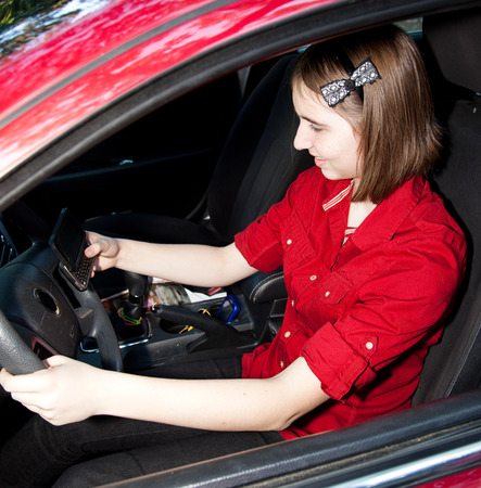 Teen girl texting while she's driving the car.  Very dangerous.